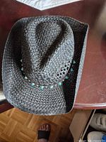 Top view of black straw cowboy hat showing crown shape, weave pattern and turquoise bead band