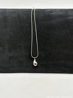 Full view of necklace on display board showing pendant and chain