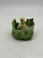 Duck figurine seated in reed bowl front view