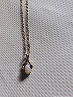 Close view of pendant showing opal cabochon set in gold tone metal