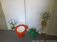 All four items grouped: flower stake, frog stake, orange mirror, green watering can