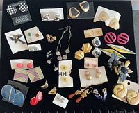 Overall view of 27 pairs of assorted vintage earrings displayed on black background