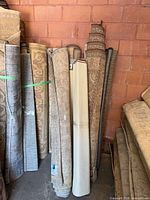 Rolled area rugs stored upright against wall