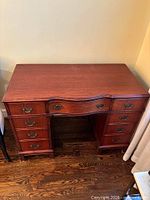Front view of wooden desk showing nine drawers and serpentine center