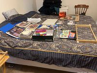 Bed covered with pattern books, magazines, hoops, supplies in box
