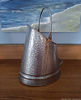 Front view of hammered coal scuttle with handle up
