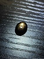 Black star sapphire displaying six-ray star under light on dark surface