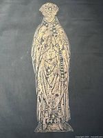 Full view of brass rubbing showing entire cleric figure on black paper