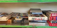 Wide shot of wire shelf with assorted hardcover and paperback books including Movie Star Chronicles and 501 Movies