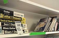 Stack of For Dummies series books and spiral-bound songbooks
