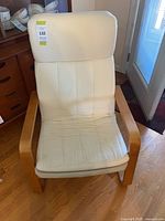 Front view of IKEA POÄNG-style armchair showing wood frame and cream cushions
