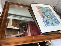 Wood-tone framed mirror and black-framed Van Gogh print stacked