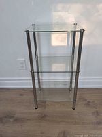 Full front view of shelving unit showing three glass tiers and chrome legs