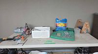 Assorted items on table including hand tools, potting mix, basket, kneeling pad, hardware