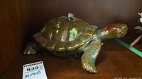 Right side view of glazed ceramic turtle figurine on shelf