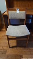 Front view of oak dining chair with beige woven fabric seat and backrest