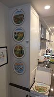 Four plates mounted vertically on wall plus boxed fifth plate on counter