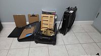 Overall view: wheeled suitcase open showing wood easel box, marker set, clipboards, canvas bag