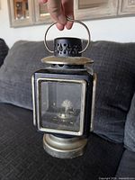 Front view of square black and brass carriage lantern with handle visible