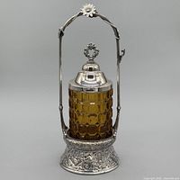 front view of pickle caster showing amber glass insert and floral silver-plate stand