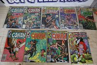 Nine comic books laid out in two rows on tabletop