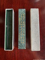 marble tablet with gold Chinese characters alongside two-piece brocade storage box