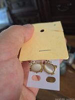 Front view of both cat stud earrings on card showing cabochons and rhinestones
