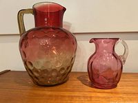 Both hobnail glass pitchers side by side on wood surface