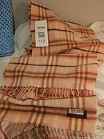 Folded scarf showing plaid pattern, fringe and lot sticker