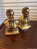 Front view of the two brass Abraham Lincoln bust bookends on tabletop