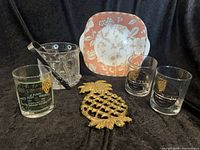Group shot of entire lot showing plate, three whiskey glasses, brass pineapple trivet, crystal ice bucket with tongs