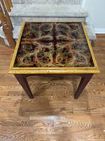 Three-quarter view of table showing legs, gold edge and decorative top