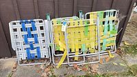 Front view of five folded aluminum lawn chairs, mixed strap colors