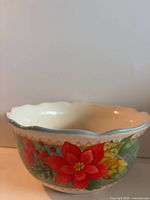 Side view showing floral design, scalloped blue rim, cream interior