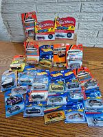 Group shot of approximately 25 carded Hot Wheels and Matchbox vehicles on table