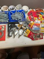 overview of table with bins of bolts, packaged hardware, chalk line reels, C-clamp