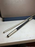 Two-piece Halex cue disassembled beside blue case