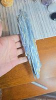 Top view of entire kyanite blade in hand showing blue coloration and length