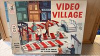 Lidded box showing Video Village artwork and branding