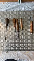 Five wood-handle hand tools arranged horizontally