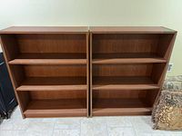 Front view of both matching brown laminate bookcases showing shelves and overall design