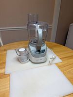 Black & Decker food processor assembled with large bowl and lid, mini-chopper bowl with lid, two cutting boards underneath