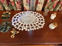 Entire lot displayed on surface showing cut glass bowl on doily, angel figurines, glass candle holder, brass hummingbird, two suncatchers