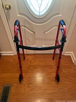 Front view of red two-wheel walker showing frame, wheels and grips