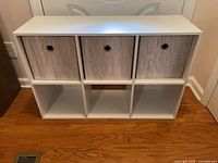 Front view showing shelf unit with three gray bins in top cubbies