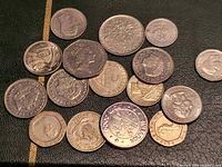 Group of 19 mixed mid-20th-century coins from five countries displayed on leather surface