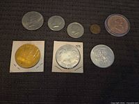 Full set of eight coins and tokens displayed on dark fabric