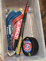 Bin holding two blue Franklin sticks, red RDX stick, Easton Hammer bat, black Canadiens puck