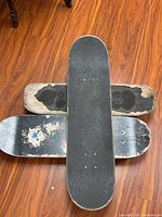 All three skateboards stacked showing grip tape condition