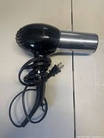 Left side view of black and chrome hair dryer with coiled cord